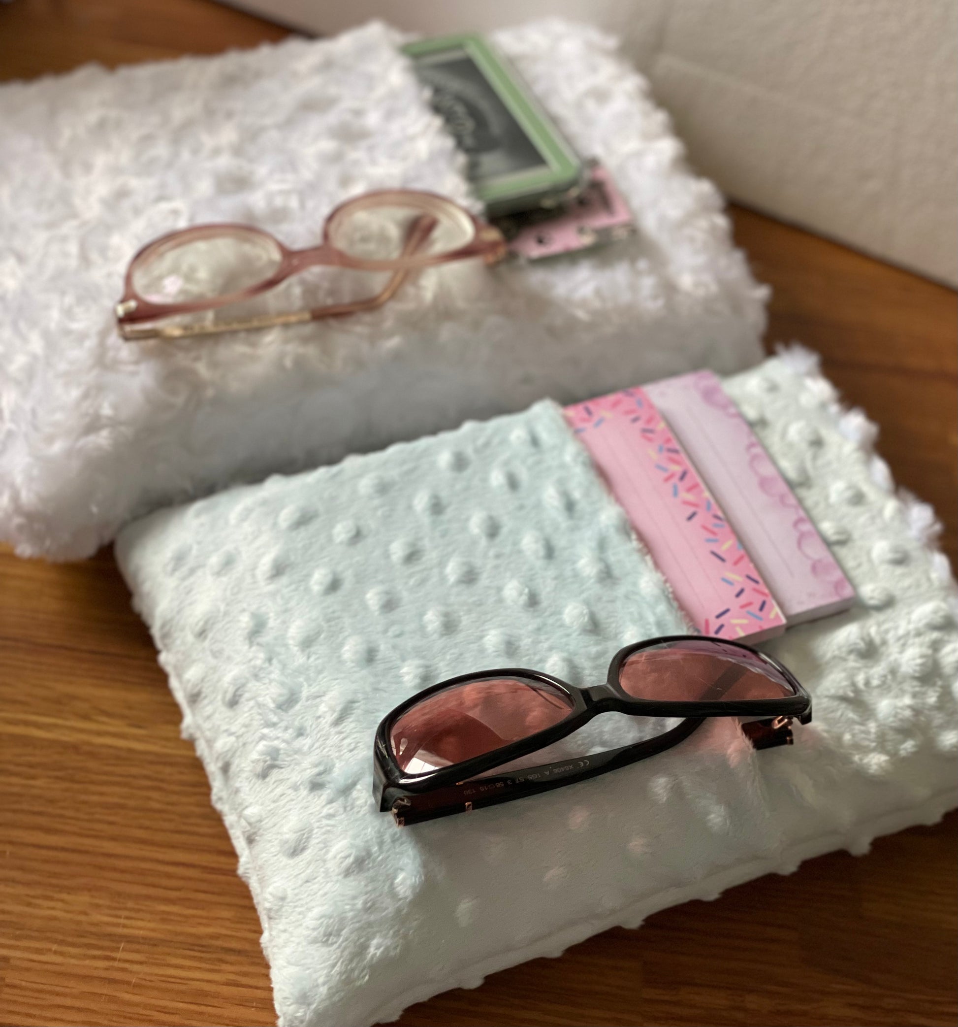White Cloud large book sleeve has a small kindle, bookmarks and a pair of glasses slid into the pocket.  Baby Blue book sleeve with two notebooks and a pair of glasses slid into the pocket size miedium. 