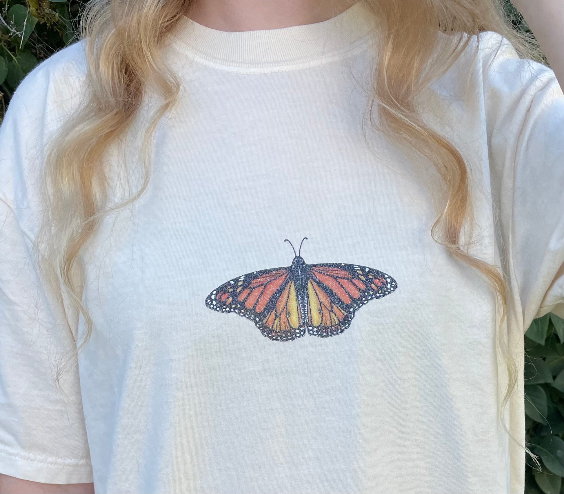 This T-shirt design has a dainty sparkly Monarch butterfly on the center front chest. 100% heavy cotton, garment dyed with a faded look and relaxed fit, ivory (ivory is slightly transparent). Sizes available: small, medium, large, XL, 2XL, 3XL, 4XL. 5XL is a Gildan T-Shirt color and texture varies slightly.