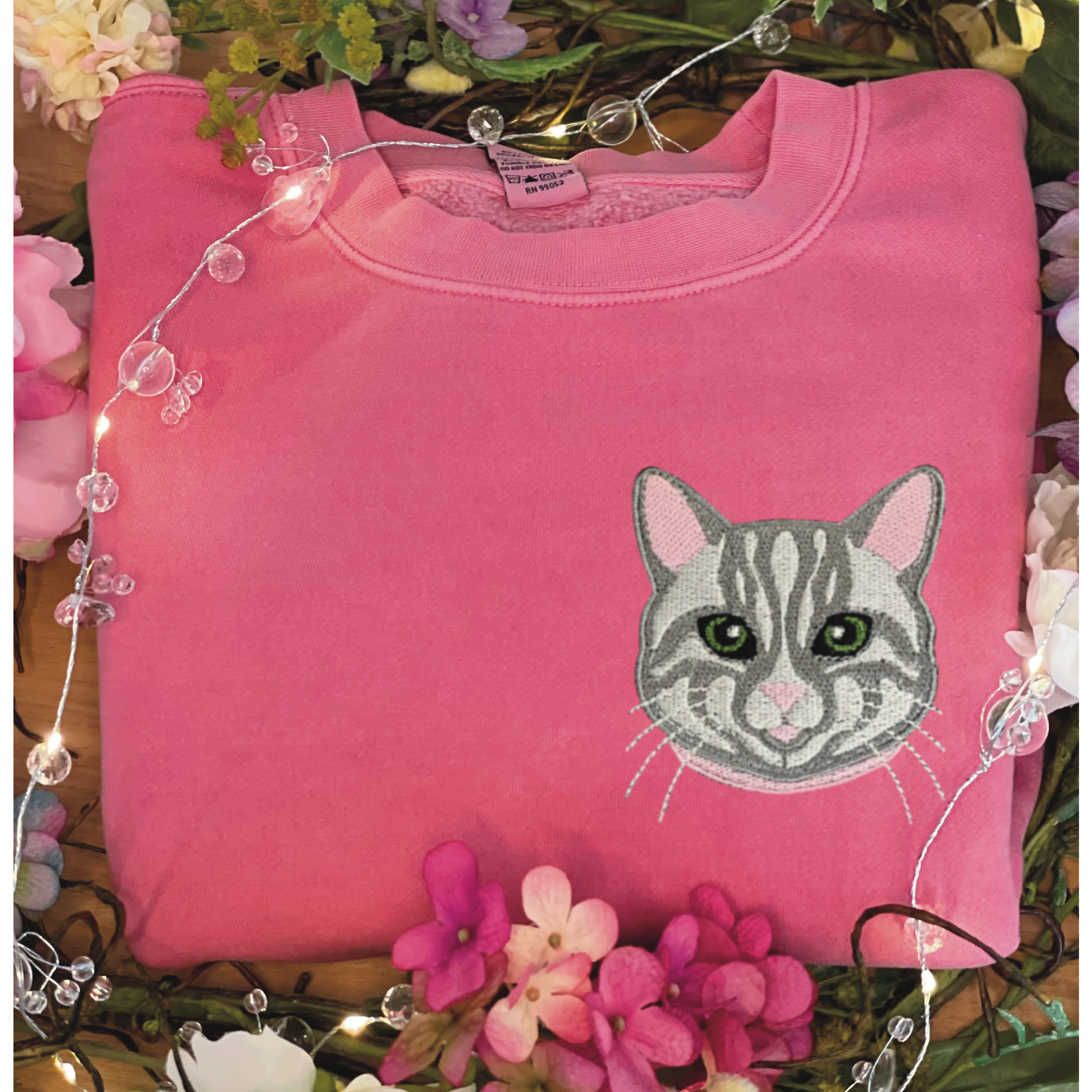 Gray Tabby Cat Embroidered Crewneck Sweatshirt. Design is 4x4 inches left chest. Available in sizes S-3XL on Pigment Pink Sweatshirt. 