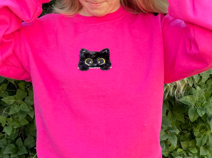 This sweatshirt crewneck is Dark Neon Pink embroidered with a super soft black fluffy (faux) fur kitty on the center front chest. Kitty looks like she is poking out of a pocket (Not a real pocket) with her big harvest gold eyes staring back at you. Unisex fit, mid-weight fabric, Material: 50% cotton / 50% polyester Blend.