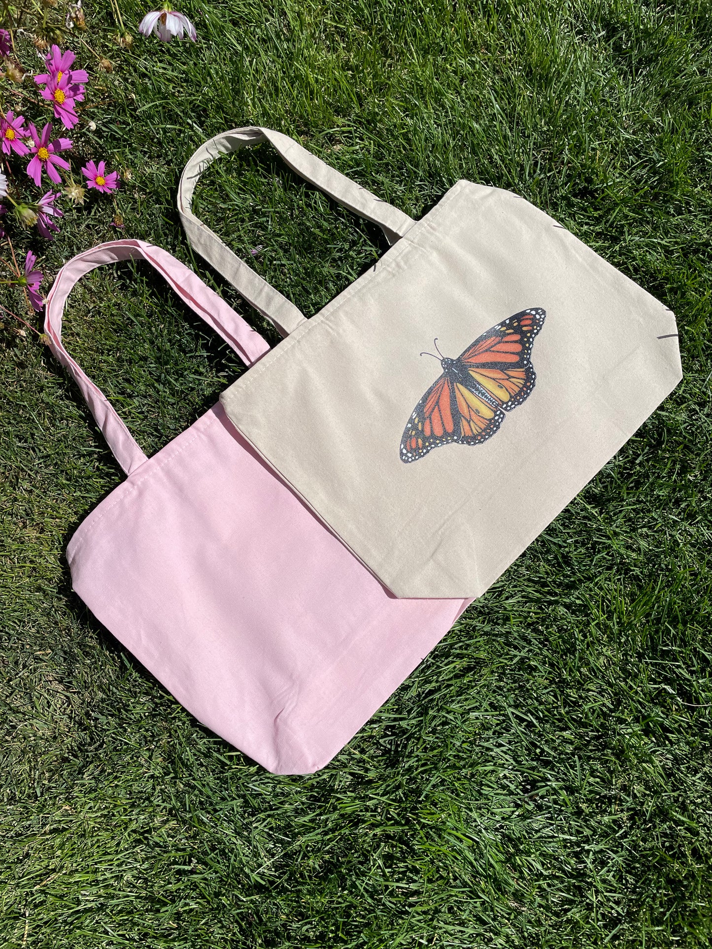 Front center of zippered tote bag large sparkle glitter Monarch butterfly with rich colors. Small version of sparkle Monarch butterfly on inside zippered pouch. Available in a light pink canvas tote or a natural tote color. 