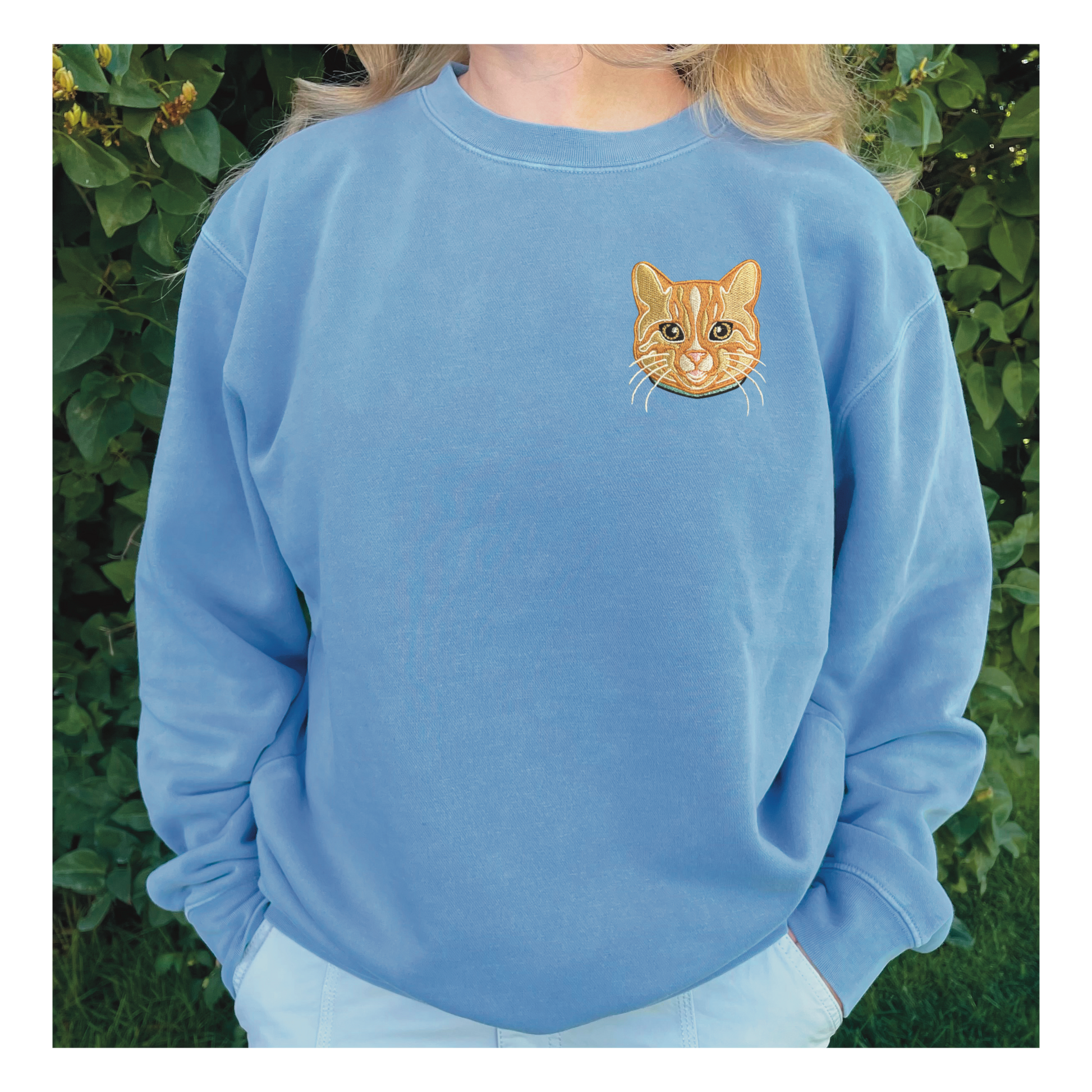 Orange Cat personalized Sweatshirt, embroidered orange cat left chest 4x4 inches. Available in sizes S-3XL. Available crew colors include pigment pink, forest green and baby blue. Shown is an orange cat embroidered on a baby blue sweatshirt. 