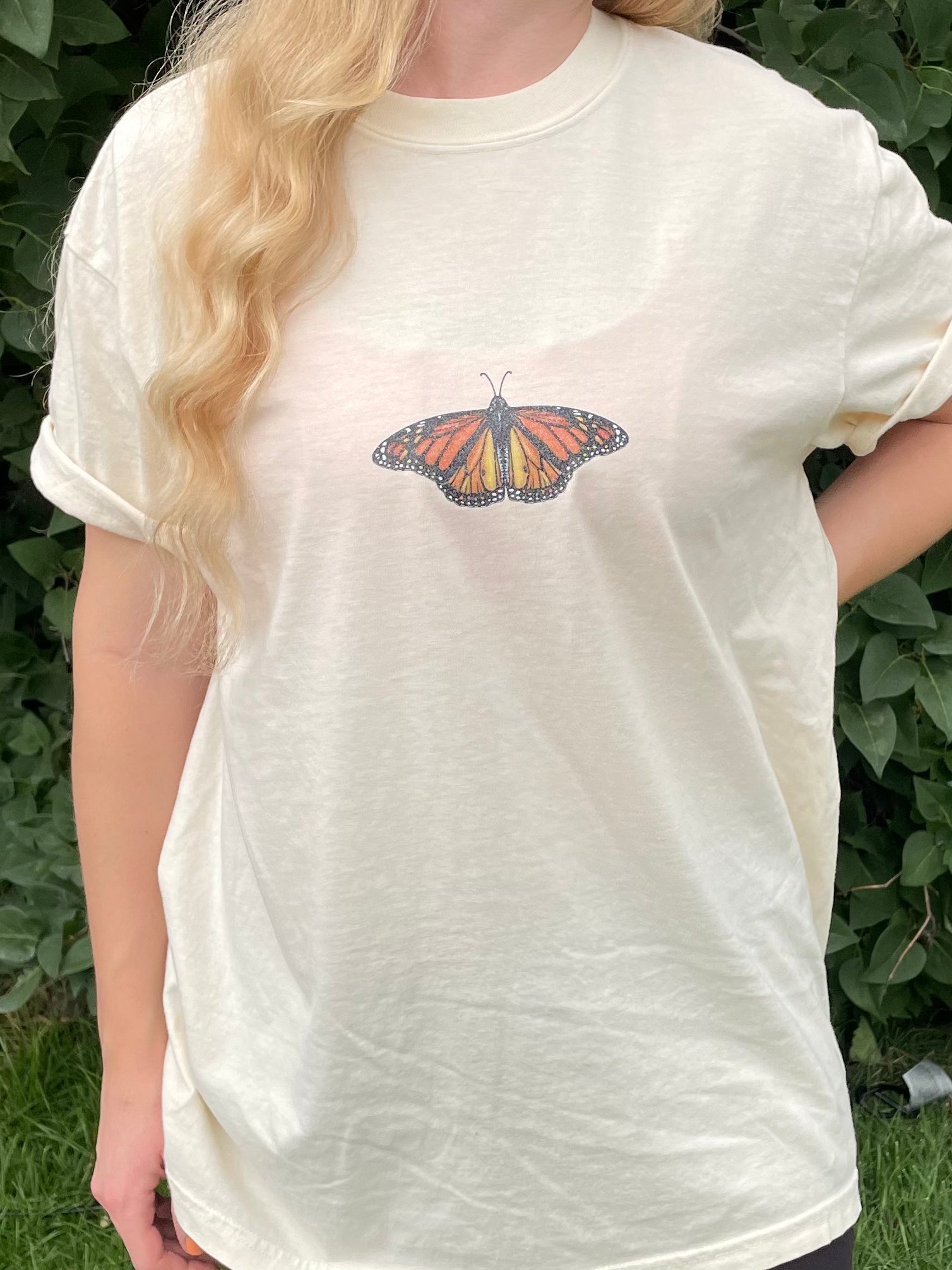 This T-shirt design has a dainty sparkly Monarch butterfly on the center front chest. 100% heavy cotton, garment dyed with a faded look and relaxed fit, ivory (ivory is slightly transparent). Sizes available: small, medium, large, XL, 2XL, 3XL, 4XL. 5XL is a Gildan T-Shirt color and texture varies slightly.