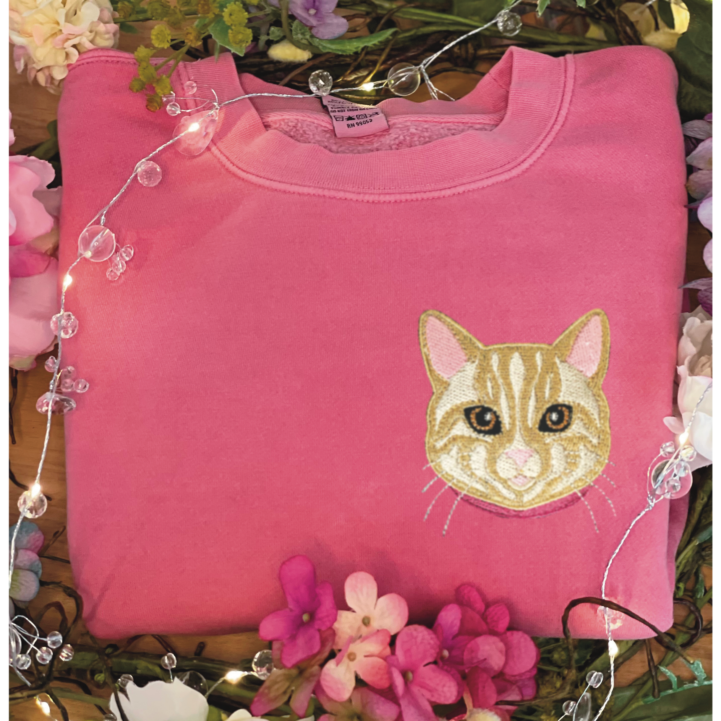 Cream/Tan Tabby Cat Embroidered Crewneck Sweatshirt. Design is 4x4 inches left chest. Available in sizes S-3XL on Pigment Pink Sweatshirt. 