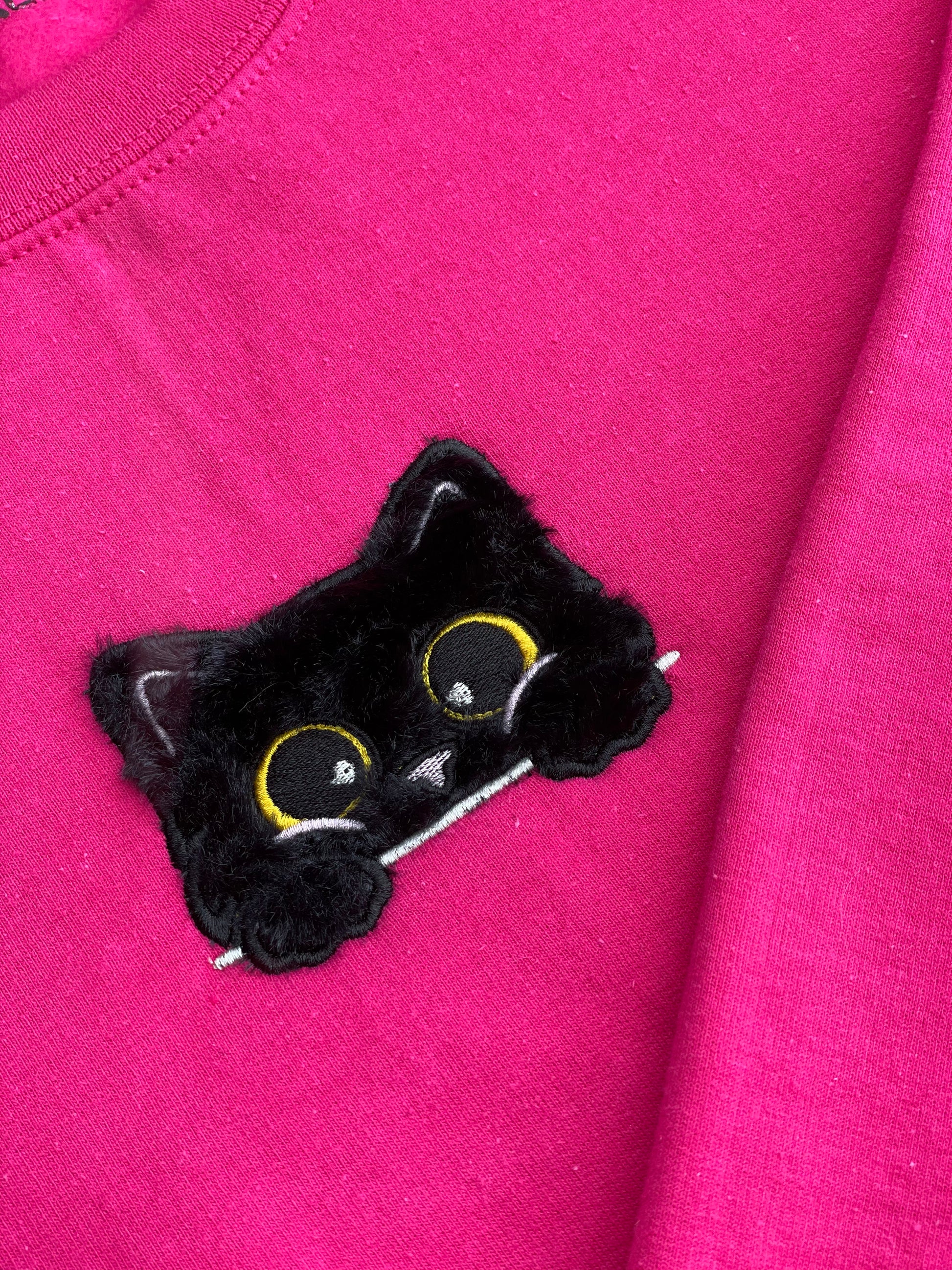 This sweatshirt crewneck is Dark Neon Pink embroidered with a super soft black fluffy (faux) fur kitty on the center front chest. Kitty looks like she is poking out of a pocket (Not a real pocket) with her big harvest gold eyes staring back at you. Unisex fit, mid-weight fabric, Material: 50% cotton / 50% polyester Blend.